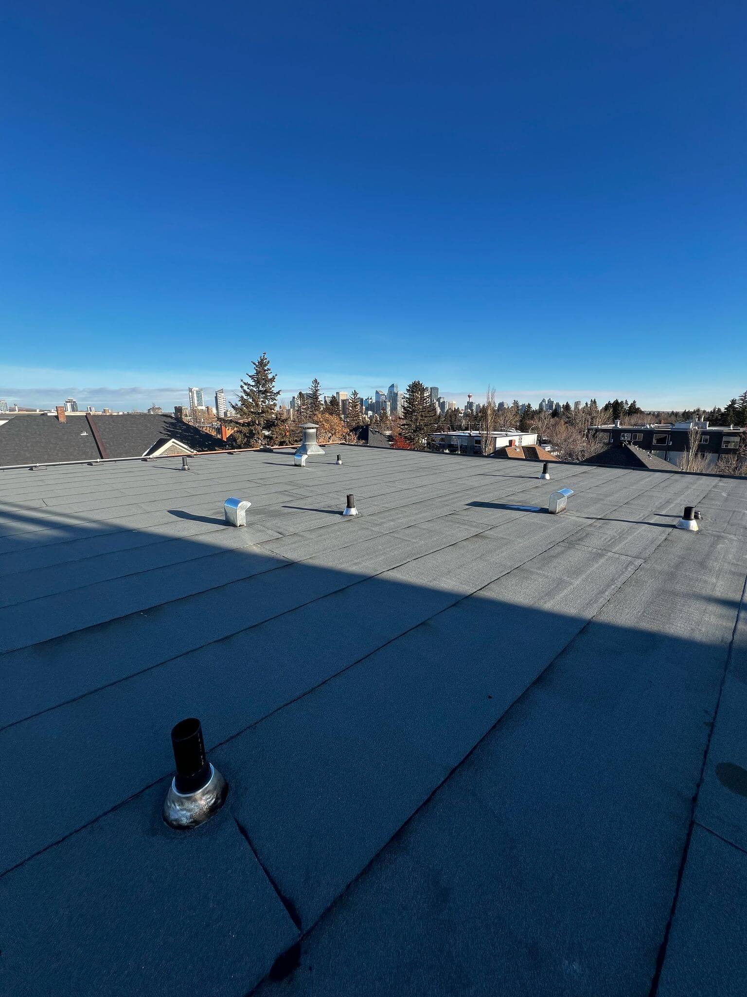 Completed flat roof installation with EPDM rubber membrane and roof vent boots in Calgary