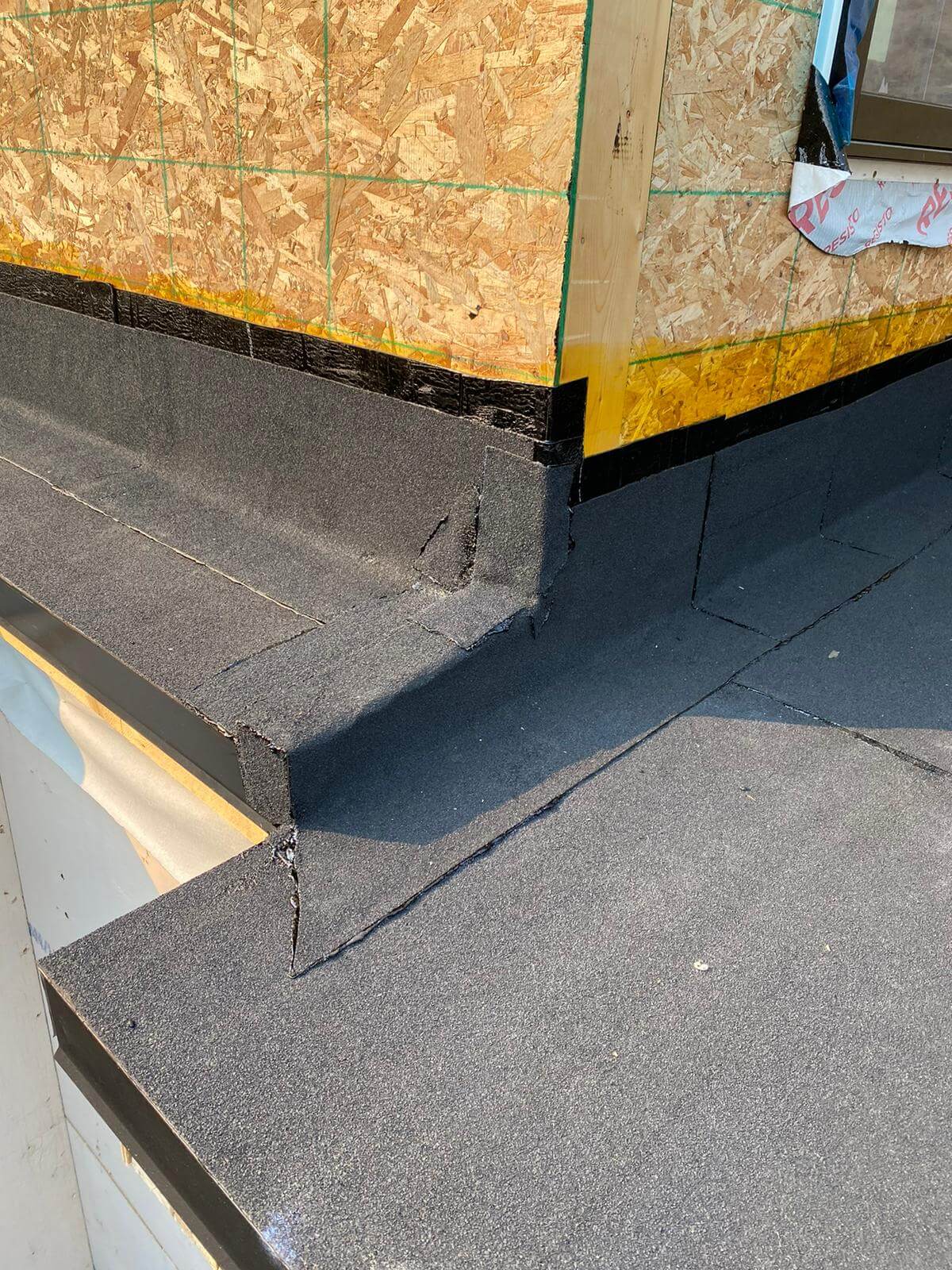 Damaged flat roof seams and flashing requiring professional restoration on a Calgary building